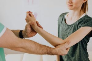Provider evaluating a patient’s elbow and wrist mobility during an upper extremity examination for elbow pain or overuse injury.