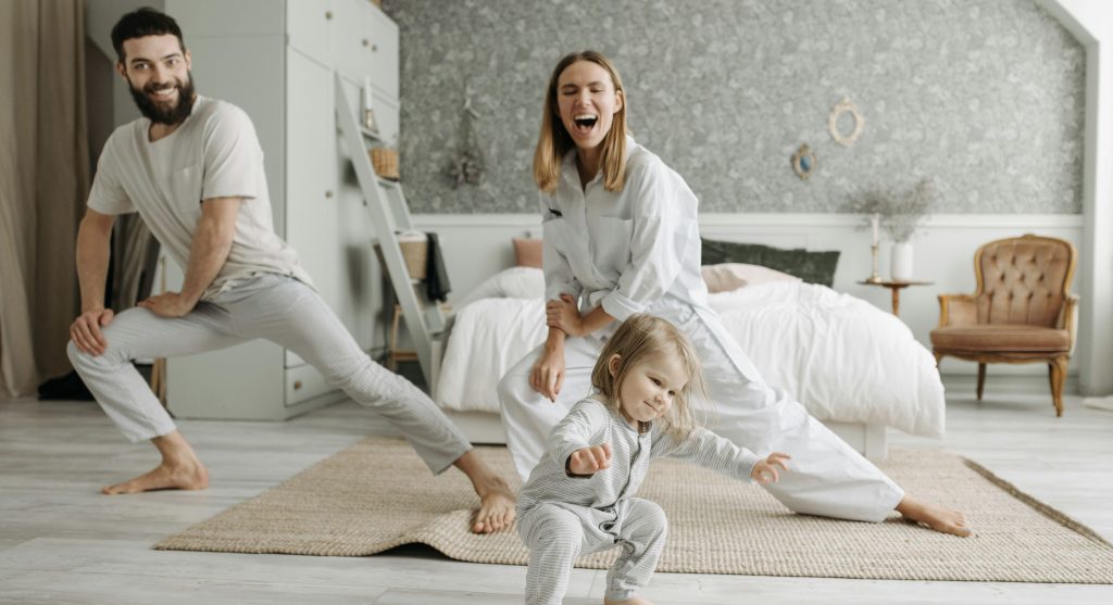 Smiling parents stretching together with their infant, demonstrating improved mobility and freedom from pain.