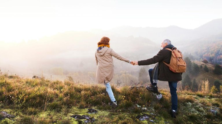 Couple holding hands while hiking outdoors, enjoying an active and pain-free lifestyle